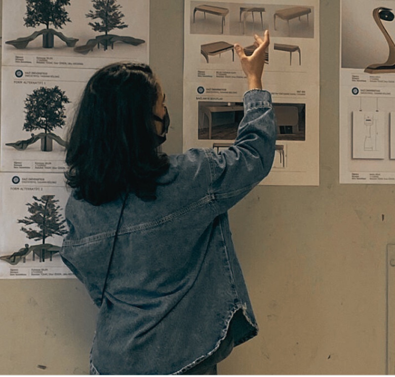 Yağmur pinning design boards to a studio wall